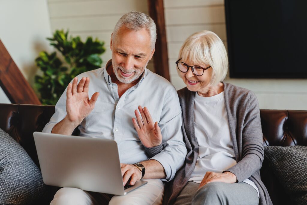 Happy old family couple waving hands looking at laptop screen doing distance video chat calling